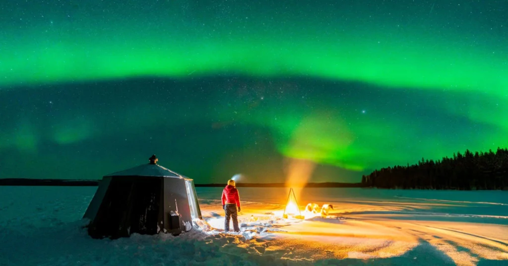 Photographer capturing the Northern Lights using a DSLR camera on a tripod