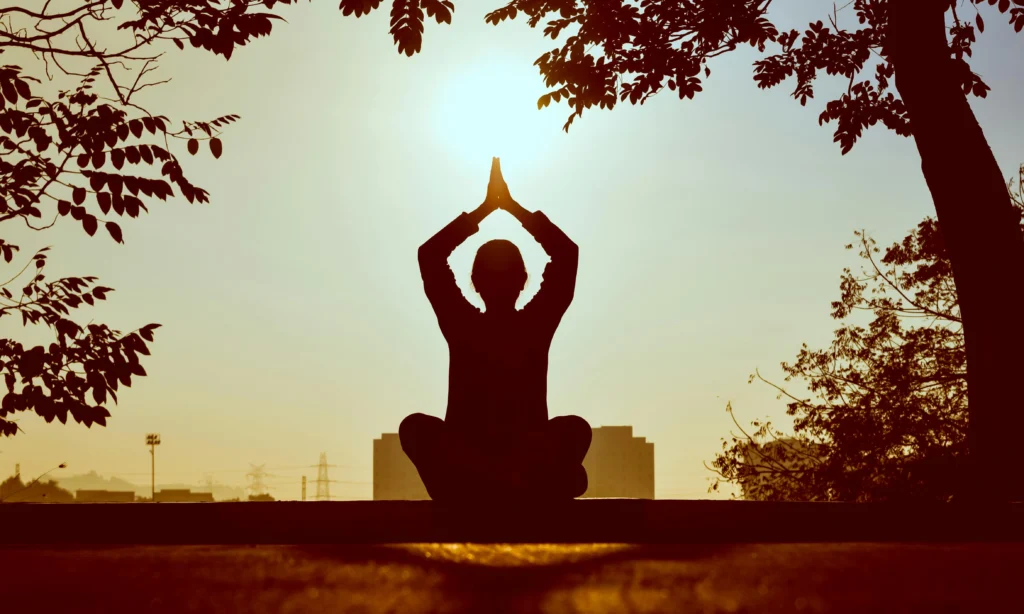 A person performing Surya Namaskar (Sun Salutation) with hands in a prayer pose and flowing through different steps.